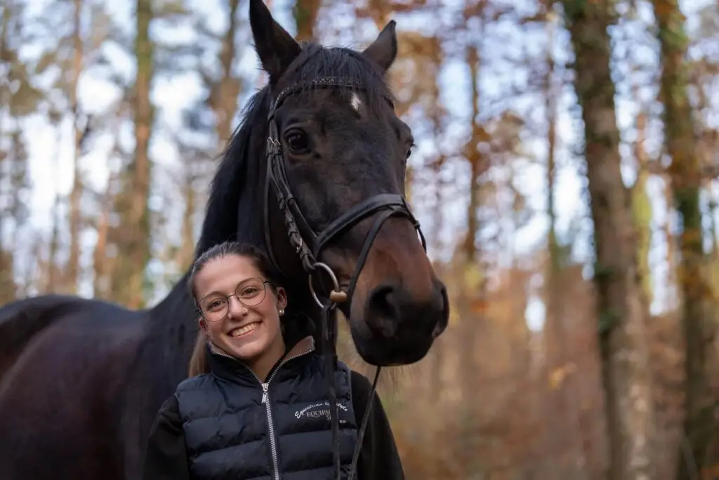 Mental Coaching: Frau von selbstbistdu.ch mit schwarzem Pferd, symbolisch für Stärke und Vertrauen im herbstlichen Wald.